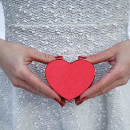 Pregnant Woman Holding A Red Heart In Her Hands In Front Of Her Belly