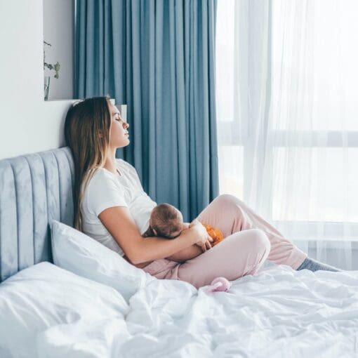 Young Mother Breastfeeds Her Baby Girl At Home.